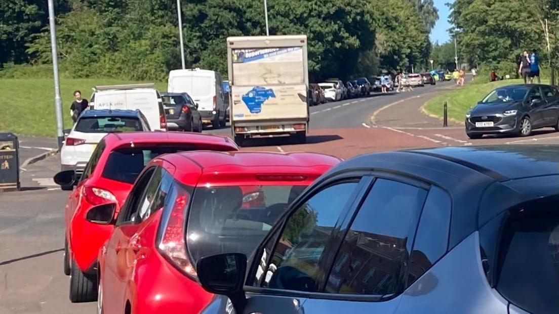 A long queue of cars lining a road.