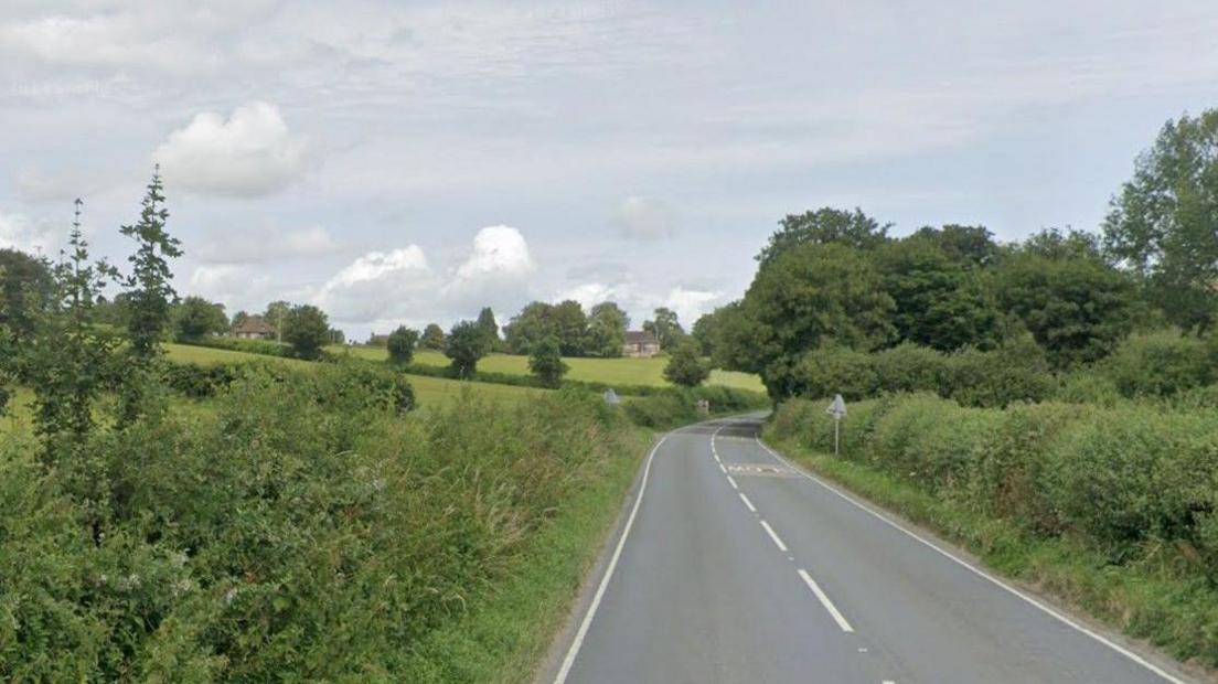 A road with white lines down the centre in a rural setting