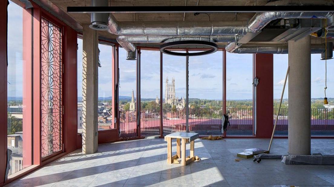 An empty room at Gloucester development The Forum is seen, with tall windows through which the city's cathedral is visible in the distance