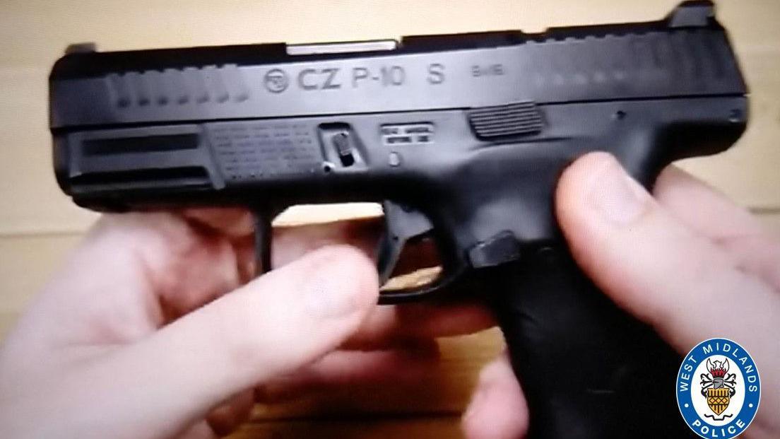 A small black semi-automatic pistol in someone's hand