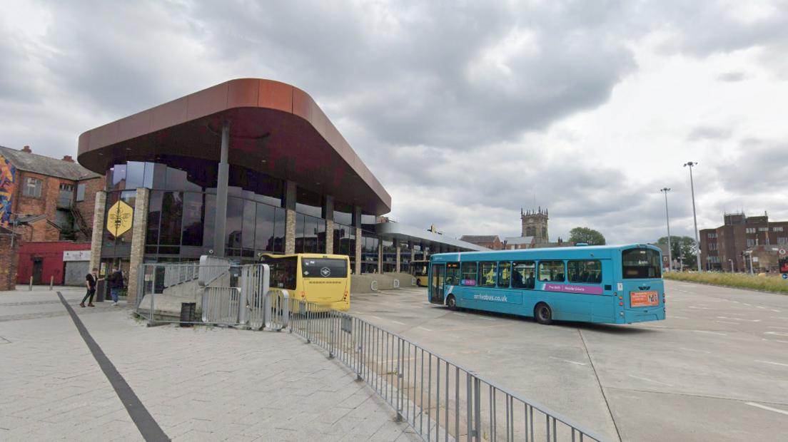 A street view image of the outside of the Wigan interchange bus station. There are two buses parked outside.