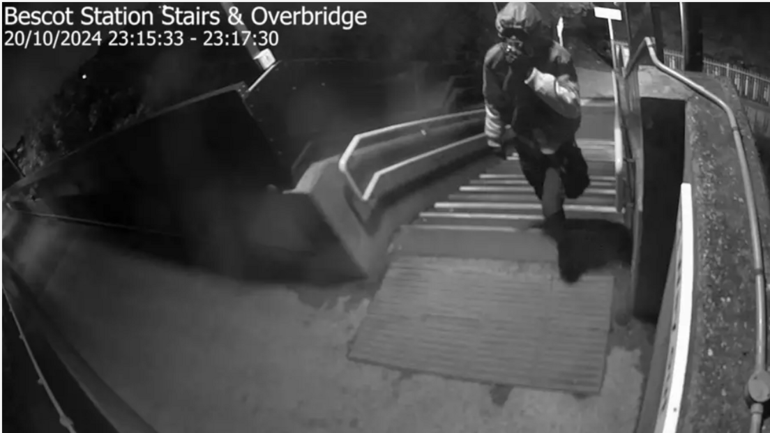 A black and white still image from CCTV footage shows a person walking up steps. At the top of the image is a time, date and location stamp