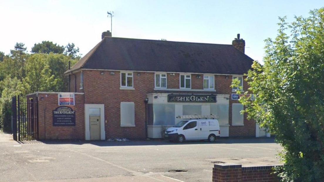 A photograph of a boarded up public house. 