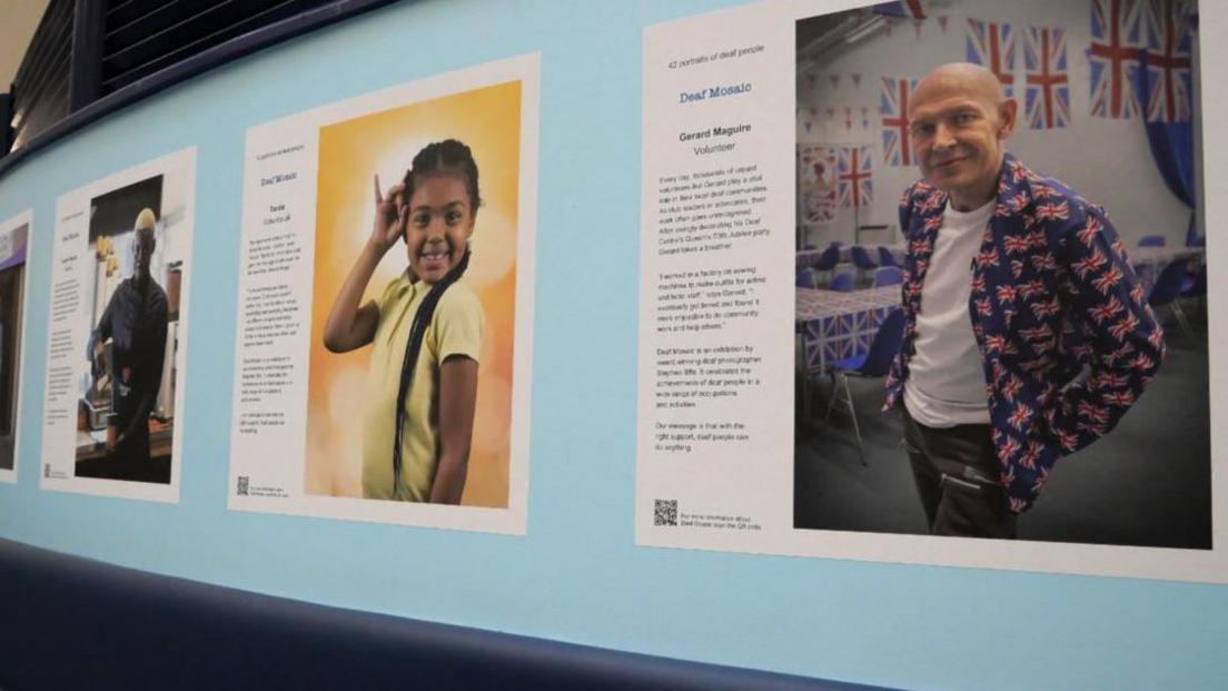 Different people in the exhibition with a different story on a wall of a hospital corridor