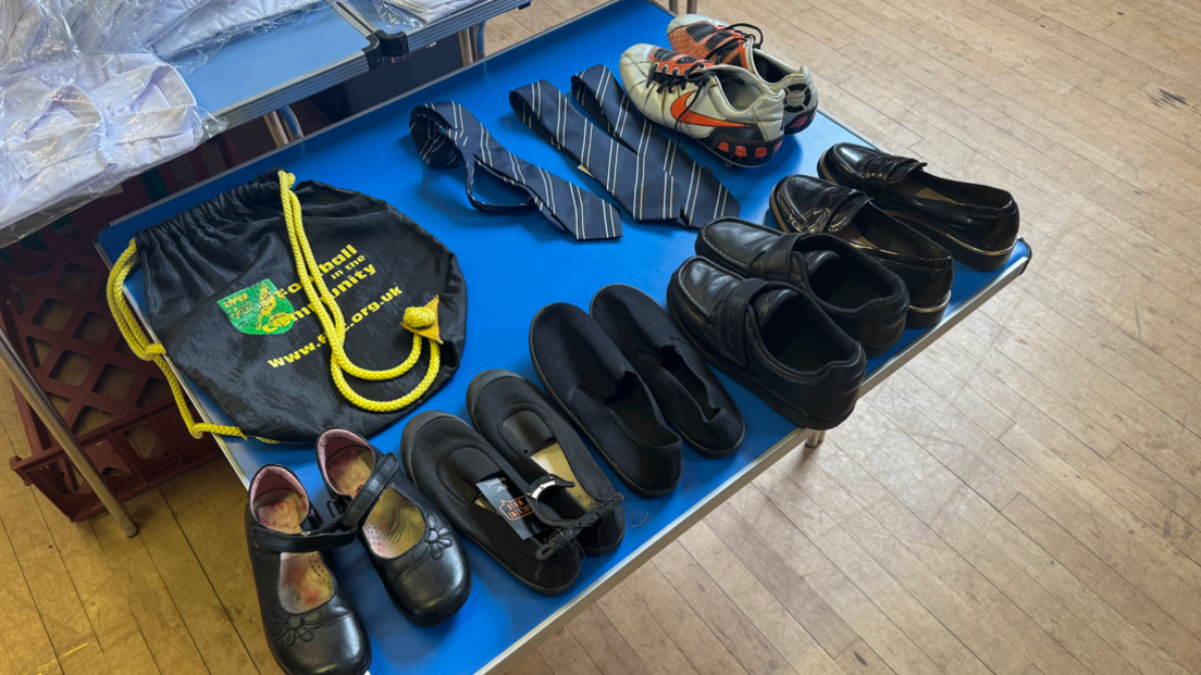 A blue table with school shoes and trainers on it.