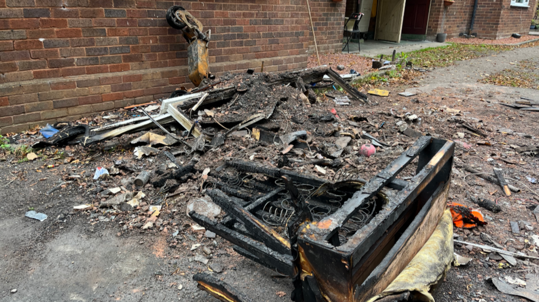 Charred possessions and a broken window frame lie on the ground below where the fire broke out