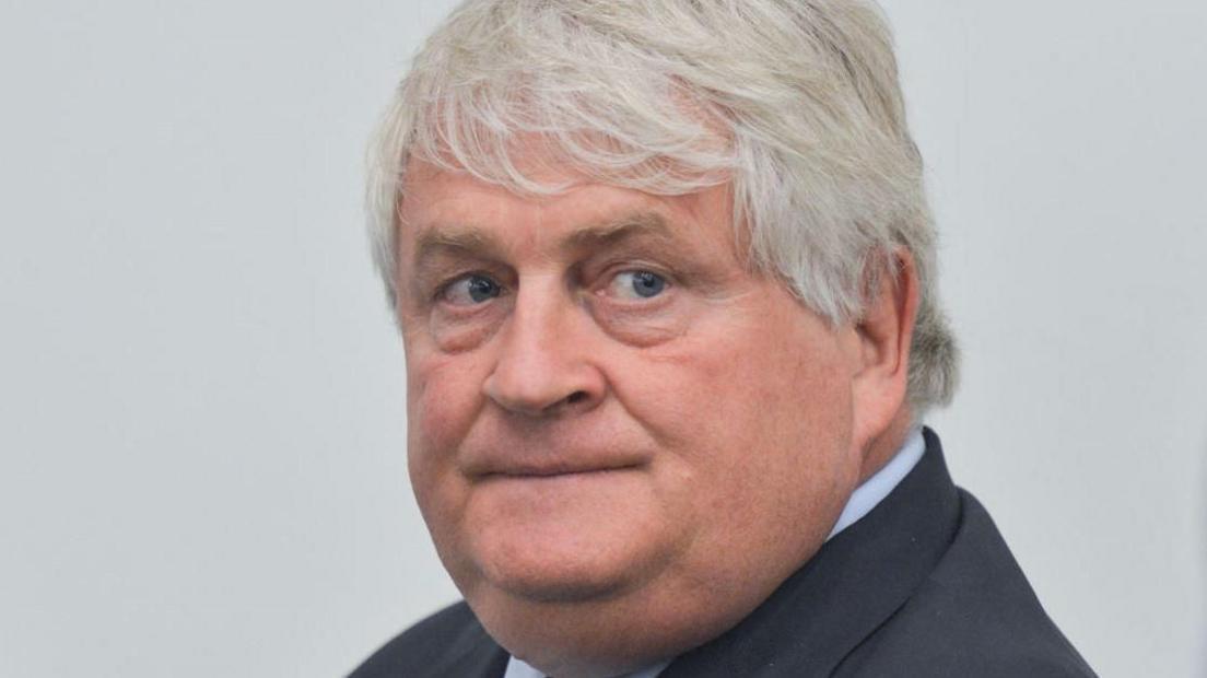 Denis O'Brien, a man with grey hair, wearing a dark grey suit and grey shirt.