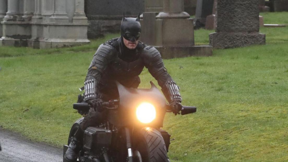 Batman riding his motorbike through a graveyard