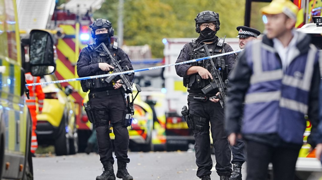 Armed police at the scene, with police vehicles in the background