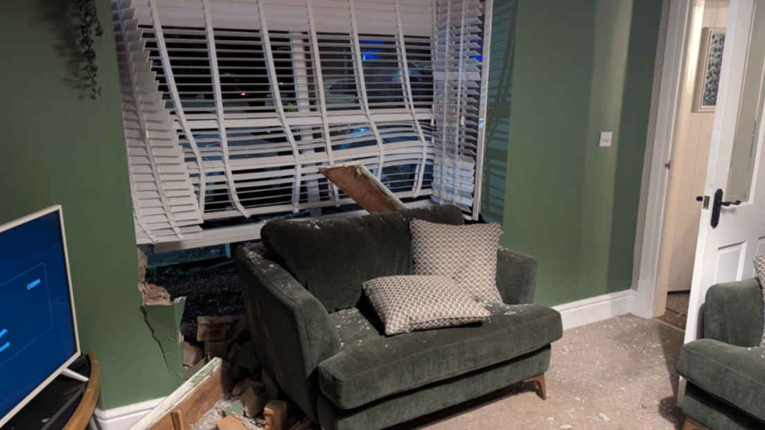 The inside of a living room with a smashed bay window