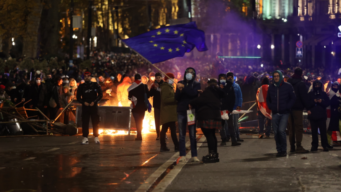 Georgian police use water cannons and tear gas to disperse protesters in Tbilisi. A man can be seen waving a European Union blue and yellow star flag against the backdrop of a fire blazing and large crowds of protests