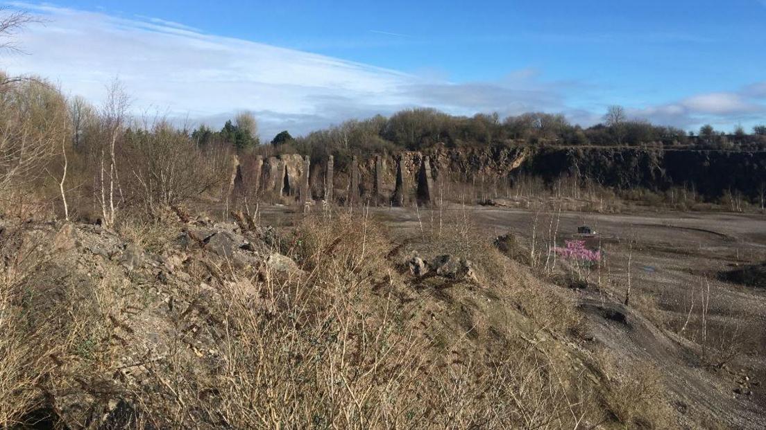 Westdown Quarry as seen from inside the quarry. It is a large open barren space with jagged rocks and twigs sticking out of the ground