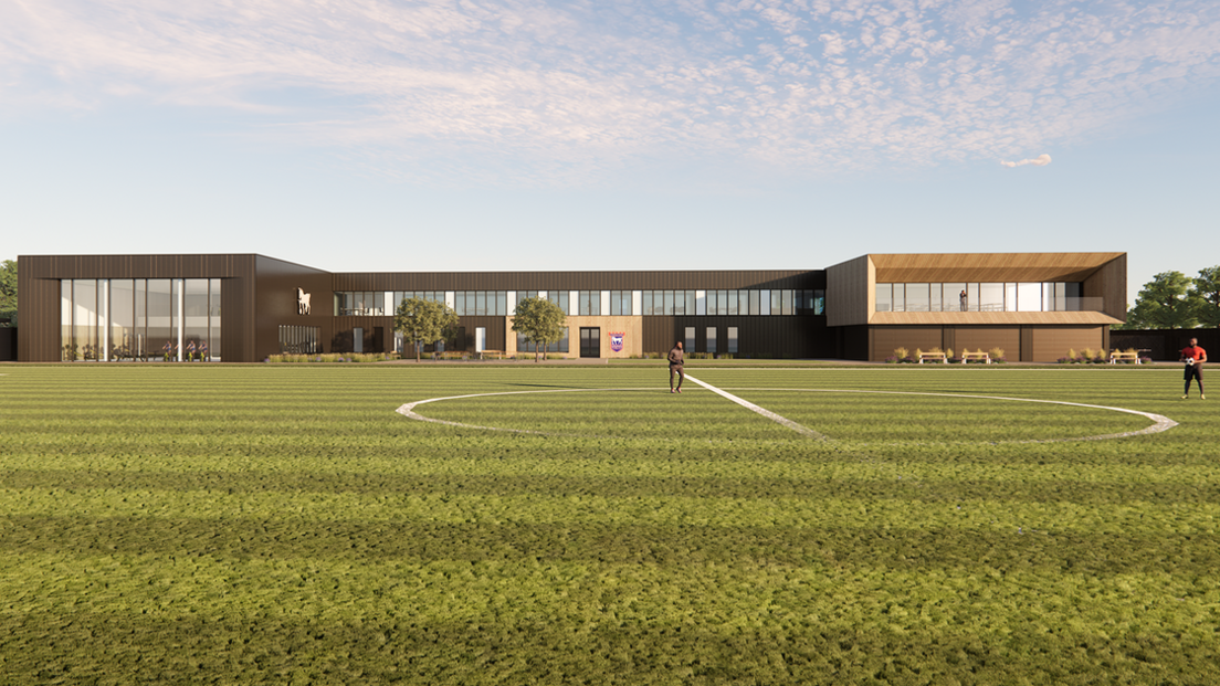 A CGI image of the new building. It is two-storey and brown, with windows across its entire length. In the foreground is a football pitch with two players standing on it. The sky is blue with a few clouds.