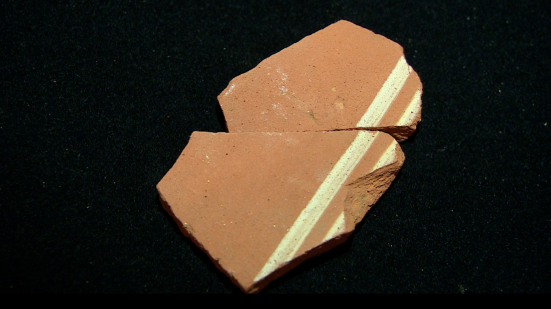 A piece of Roman pottery with two white lines running parallel to eachother