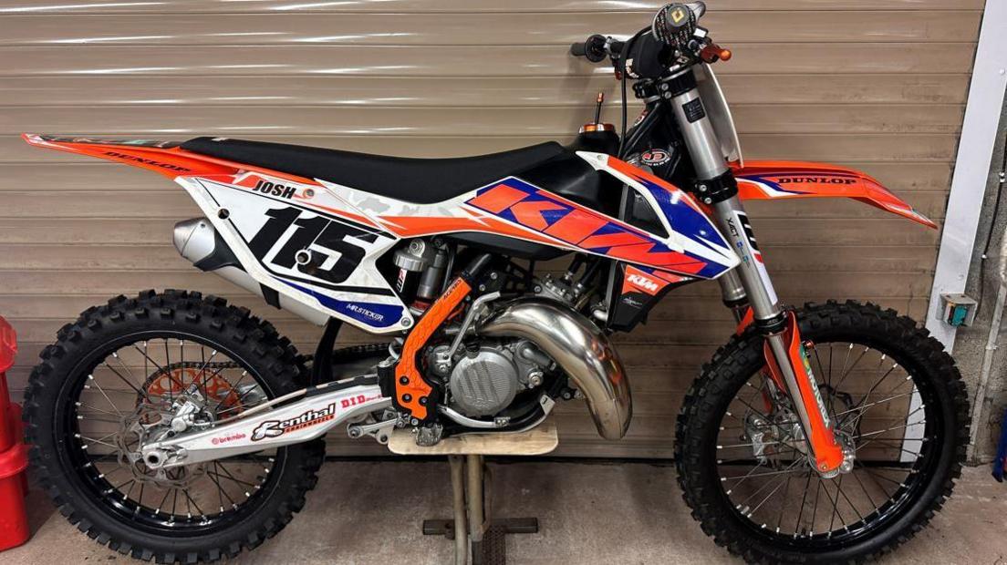 An orange and black KTM 125 motocross motorbike inside a garage