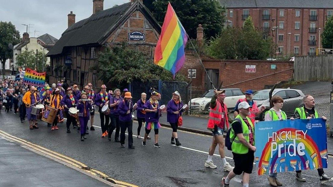 A view of the Hinckley Pride parade in 2024, with a giant rainbow flag flying in the air.