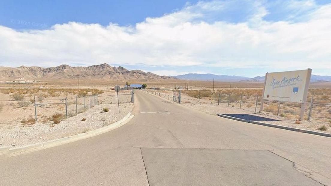 Jean Airport in Nevada showing the blue and white sign to the airport on the right and the road leading to the runway.