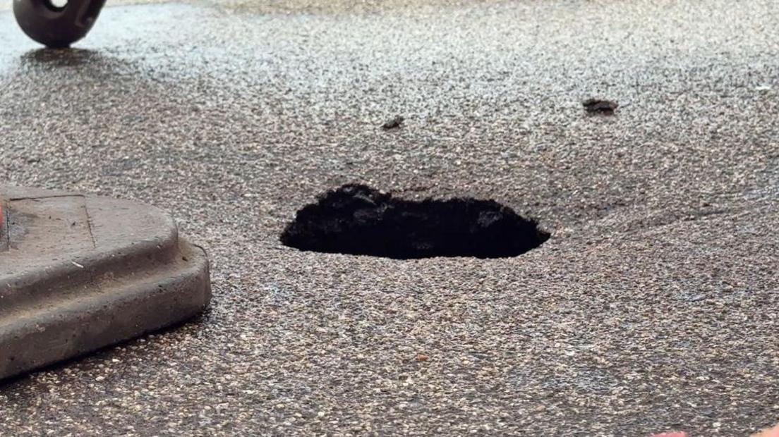 A tarmac road with a hole the size of a football.