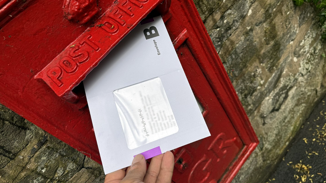 a postal vote being posted in a red post box