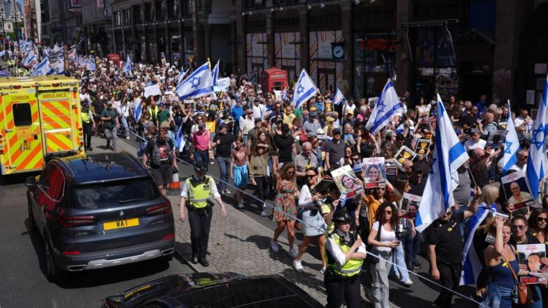 Thousands of people march with Israeli flags, placards and images of hostages