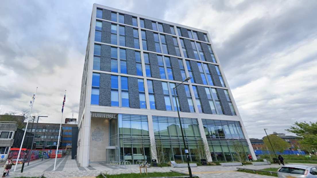 The medium-rise town hall building in Crawley on an overcast day. The lower floors of the building are mostly glass-fronted while the upper floors have smaller windows and grey cladding.