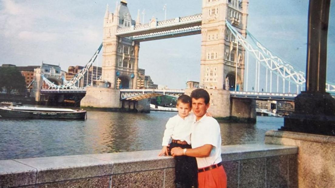 Mr Duraku standing in front of Tower Bridge in 1998 with his young son. 