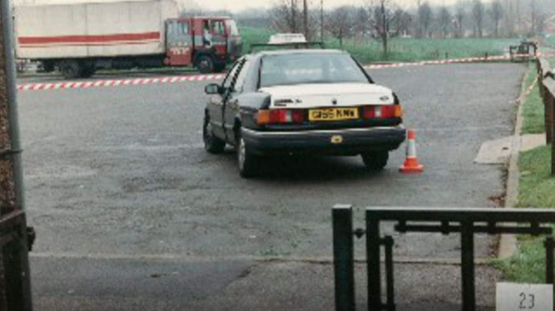 A photograph taken in 1994 of a crime scene, showing a taxi next to playing fields in Gedling, with a lorry parked in the background