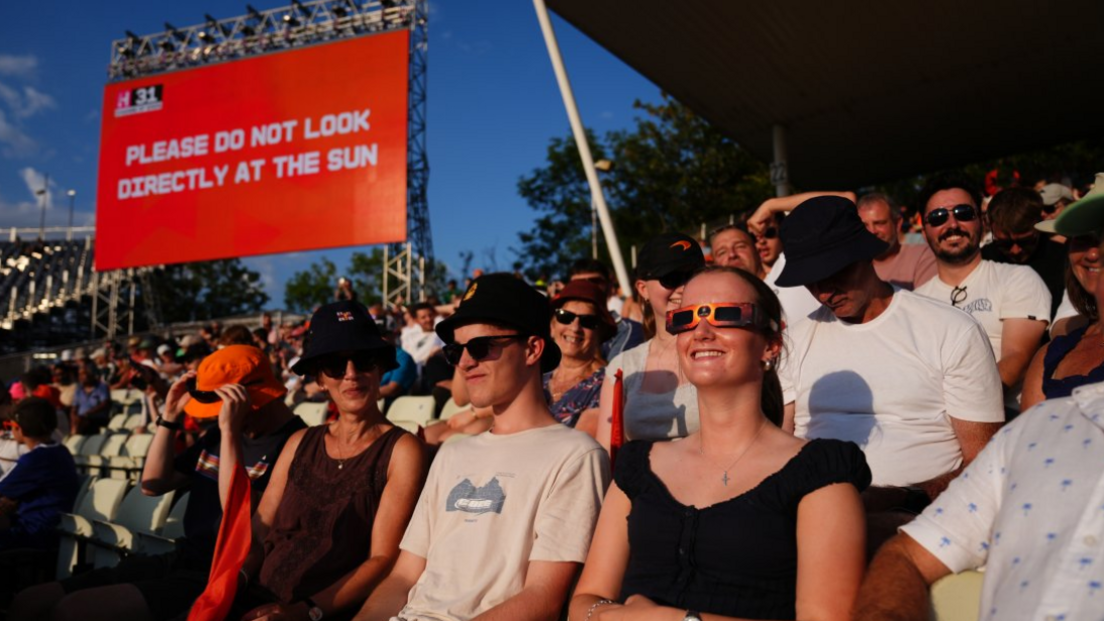 Spectators in the stands uses special eclipse glasses to watch the solar eclipse during The Hundred men's match at Edgbaston
