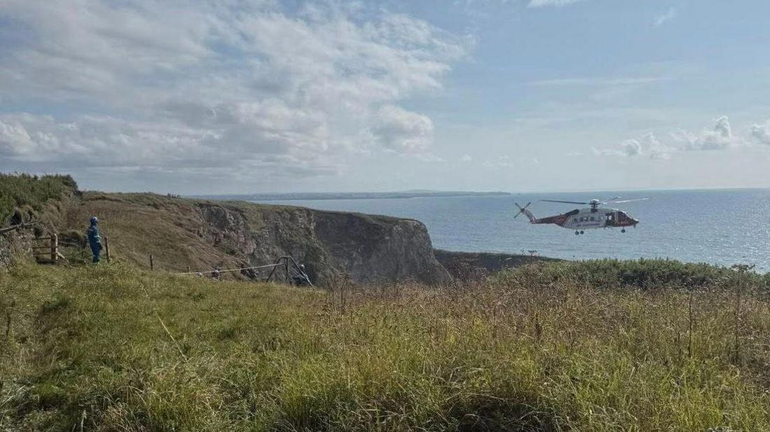 The helicopter hovering near the cliffs