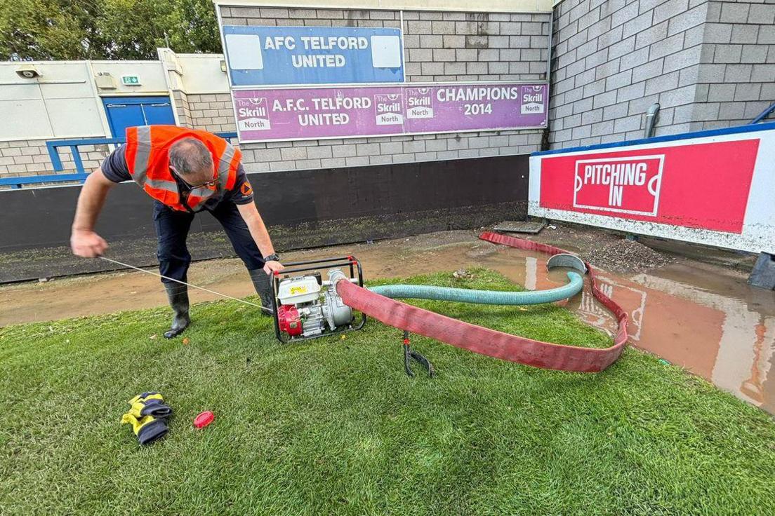 A man is using a pump to remove flood water from the football ground