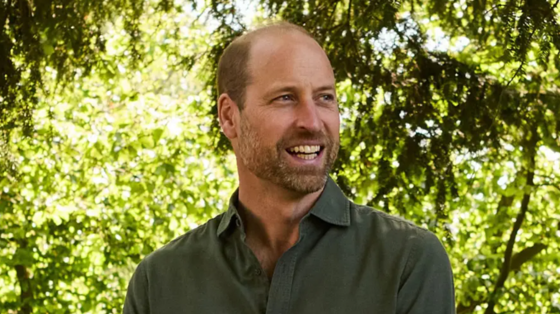 Prince William, standing by trees, wearing a dark green shirt