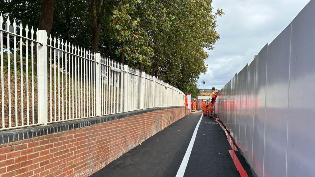 The improved walkway at Botley Road in Oxford, leading towards Frideswide Square, winding by a wall at Oxford Station. Some workers could be seen at the end of it.