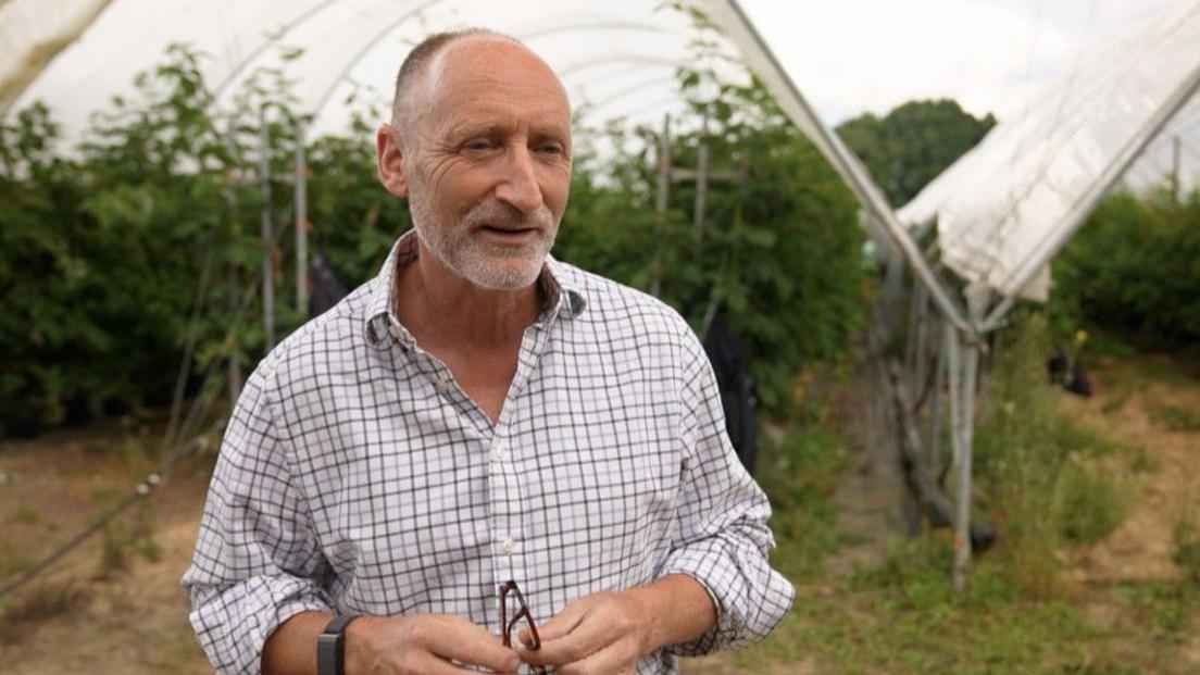 A farmer in a checked shirt speaks to the BBC