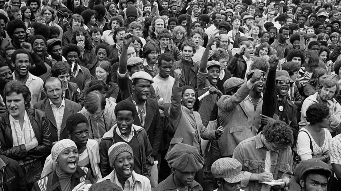 Black and white image of anti-racists gathering to block route of National Front demonstration, New Cross Road, London, August 1977