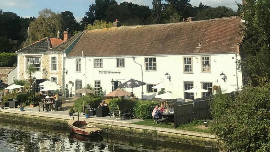 Rushcutters pub in 2020, as pictured from rail bridge. People are sat outside, and a boat can be seen in the water