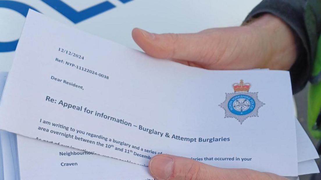 A man holds a bundle of letters dated 12 December 2024 and bearing the force's logo. The letter's subheading reads: re: appeal for information - burglary and attempt burglaries