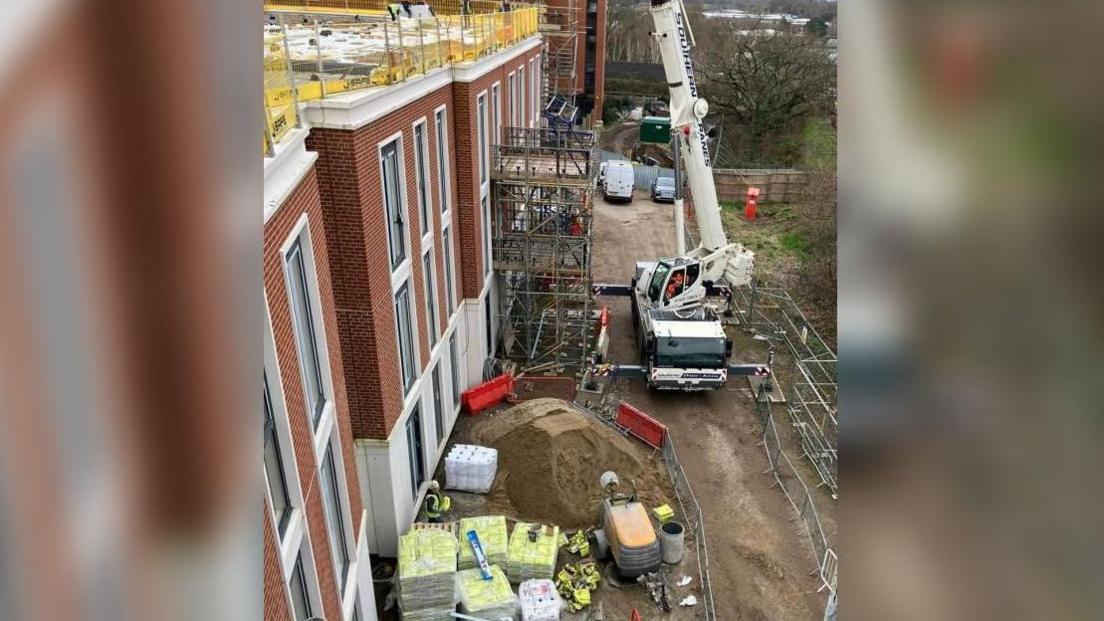 construction site with crane and fenced-off area with building supplies