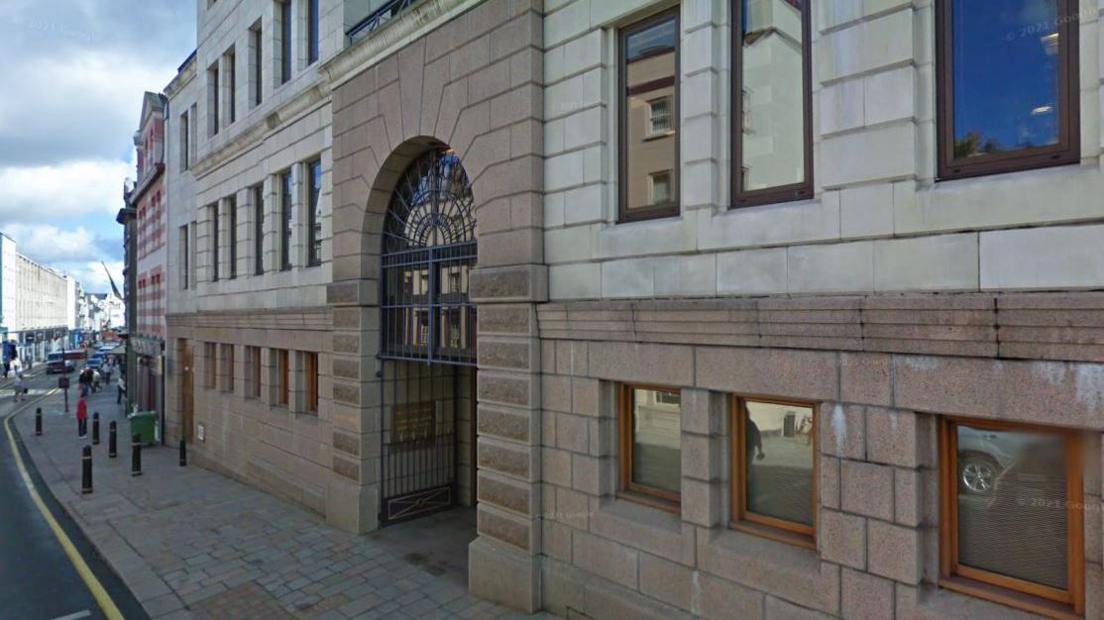 Google Street View of Morier House in Jersey, which has brown and grey brickwork, several windows across three floors and a set of railings at the front entrance