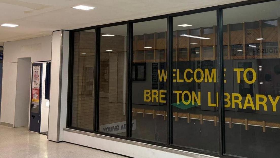 Exterior of Bretton Library: a window marked, in yellow, with the words: "WELCOME TO BRETTON LIBRARY"
