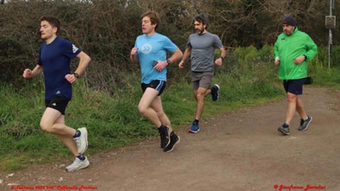 Ian Williams and his brother Evan on a running track in Caffarella Park. Ian leads the pack with the dark blue t-shirt, his brother is just behind followed by two other runners.