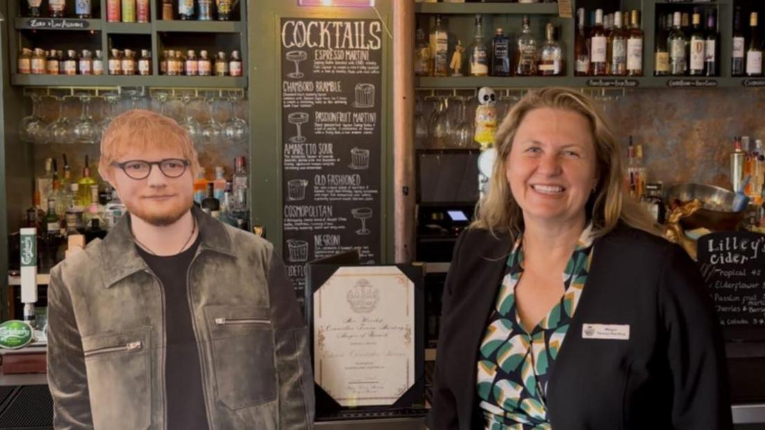 Teresa Harding, mayor of Ipswich, in Australia, standing behind a bar next to a life-sized Ed Sheeran cardboard cut out.