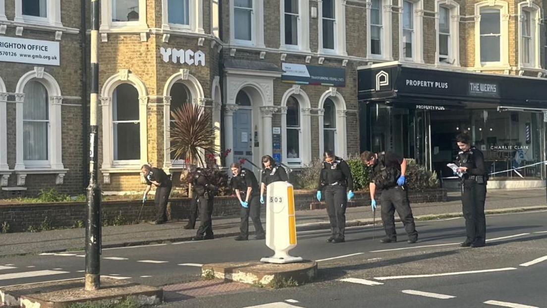 Police officers sweeping a street for evidence