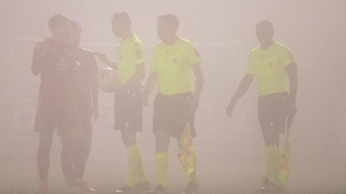 The officials speaking to the managers with fog making it hard to see any of the people in the photograph (it's basically an illustration of fog)