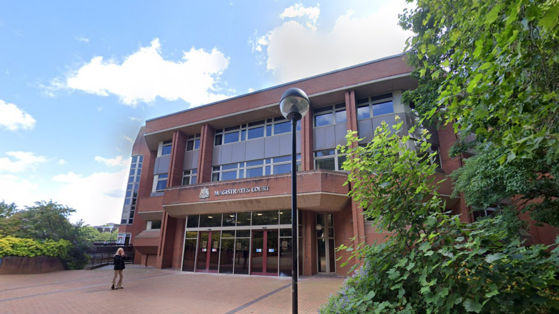 Coventry Magistrates Court, a brick building which lots of front-facing windows surrounded by bushes