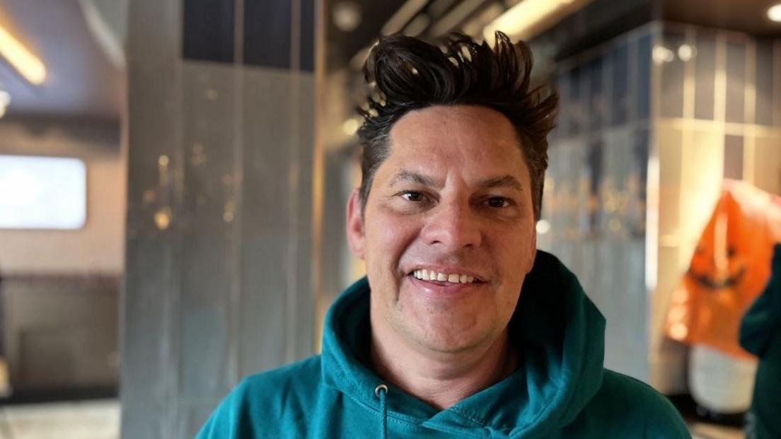 Mark Ackred, co-founder of CounterSpike wearing a green hoodie. He has black spikey hair and is smiling at the camera.