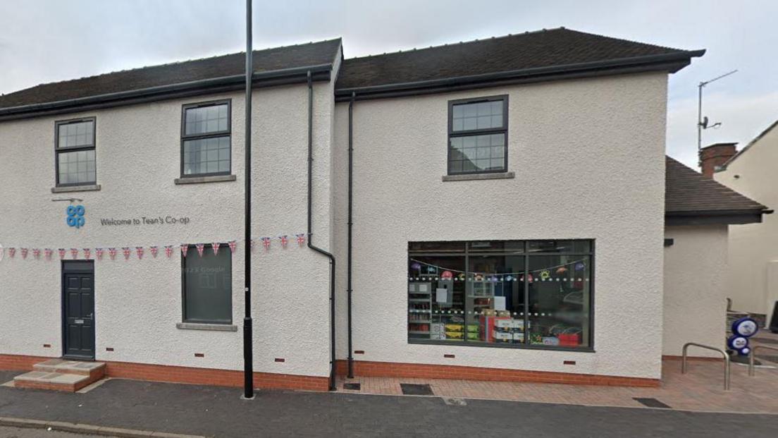 A google street view image of a cream brick building with large shop windows. 