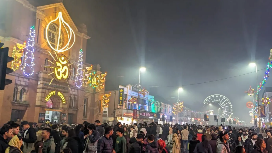 Hundreds of people gathering in a road in Leicester which is lit up with decorative lighting