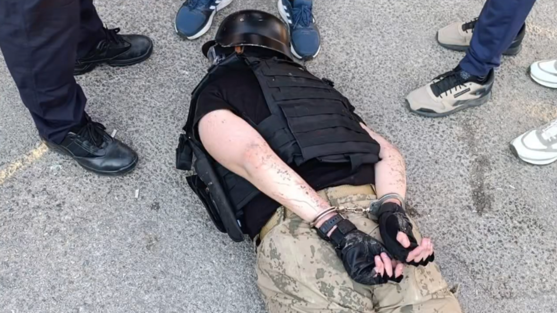 The suspect lying face down on the street while handcuffed after being detained by police.