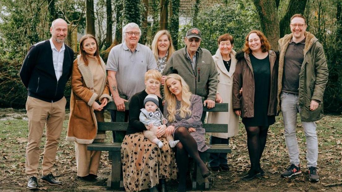 Alison and Rachel on a bench surrounded by their families