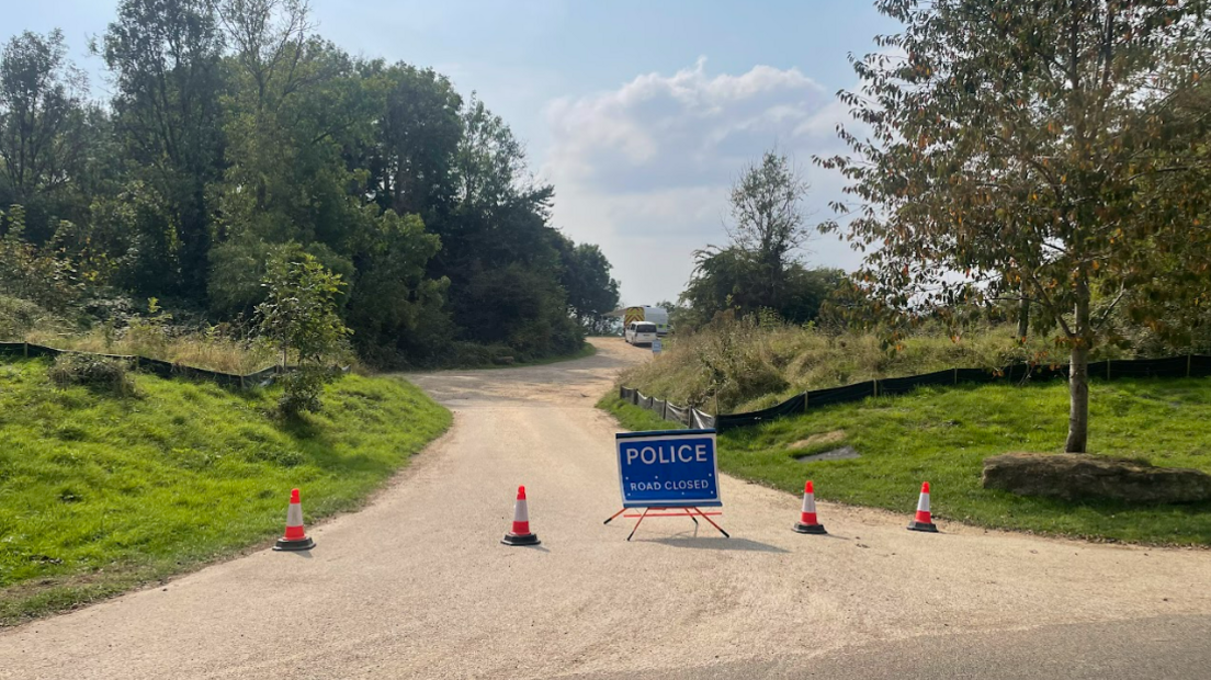 A road closure at Ham Hill with a blue police sign and police cars in the distance.